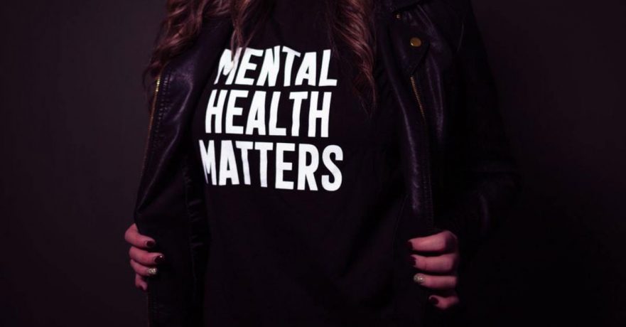 closeup image of a woman opening her jacket to display a mental health awareness shirt