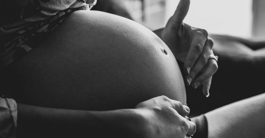 black and white closeup image of a pregnant woman's stomach